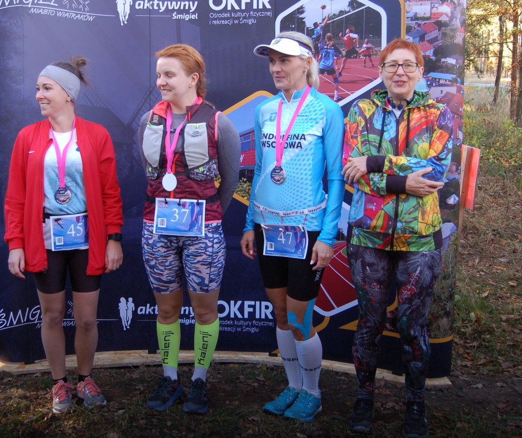 uczestniczki imprezy z zawieszonymi medalami za udział na tle baneru